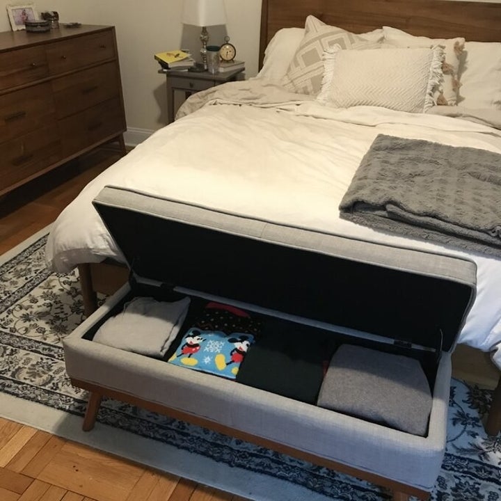 a reviewer photo of the gray storage bench at the foot of the bed with the lid open