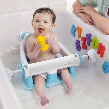 A baby sitting upright in the bath seat