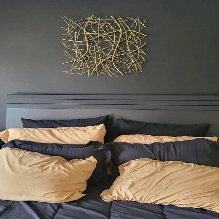 a reviewer photo of the gold sculpture above a bed