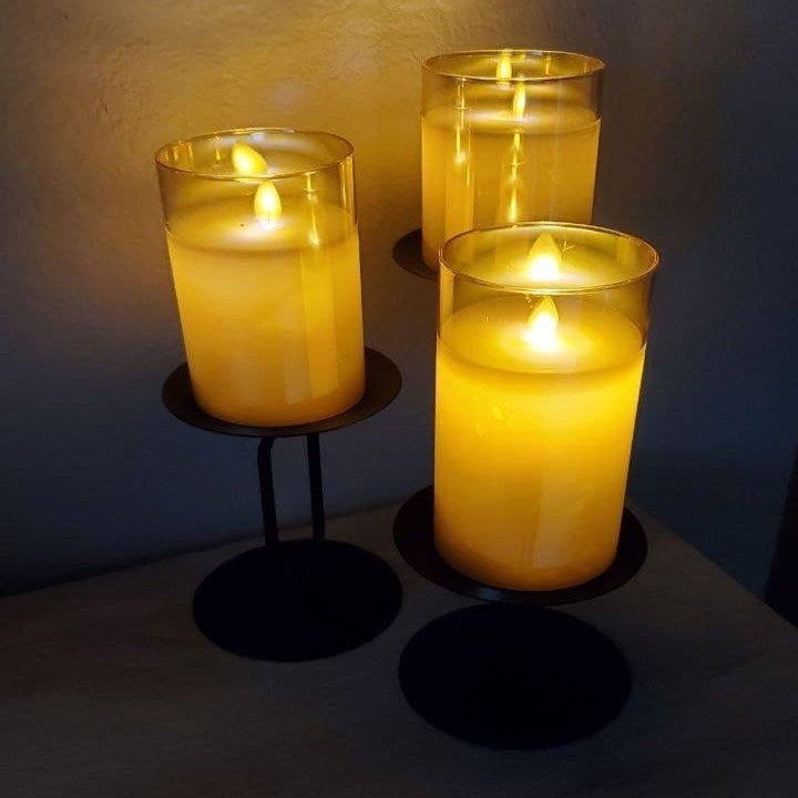 three flameless candles arranged on stands of different heights