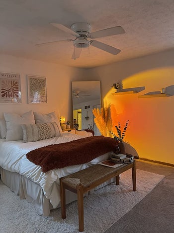 the sunset lamp casting a warm orange-yellow glow onto the wall of a reviewer's bedroom