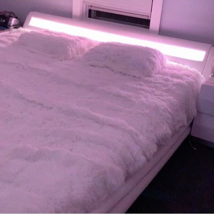 the same reviewer's photo of the bed in a different pink lighting