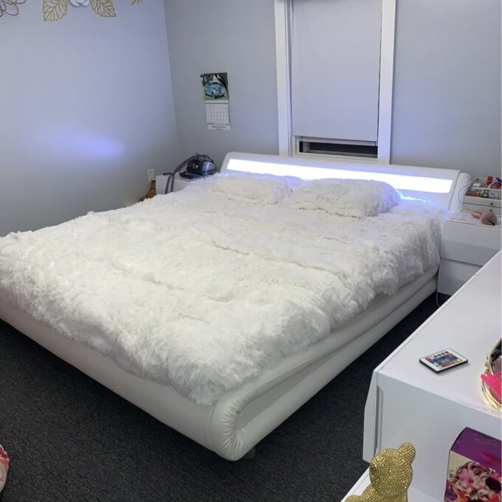 a reviewer photo of the white bed with white fluffy bedding