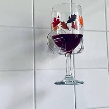 a reviewer's wine glass held by the cupholder caddy on a shower wall