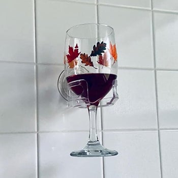 a reviewer's wine glass held by the cupholder caddy on a shower wall