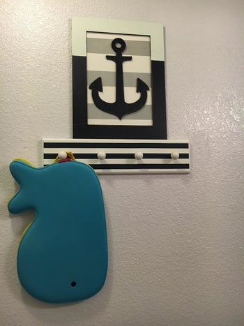 reviewer's photo of the whale-shaped bath kneeler hanging from a towel hook