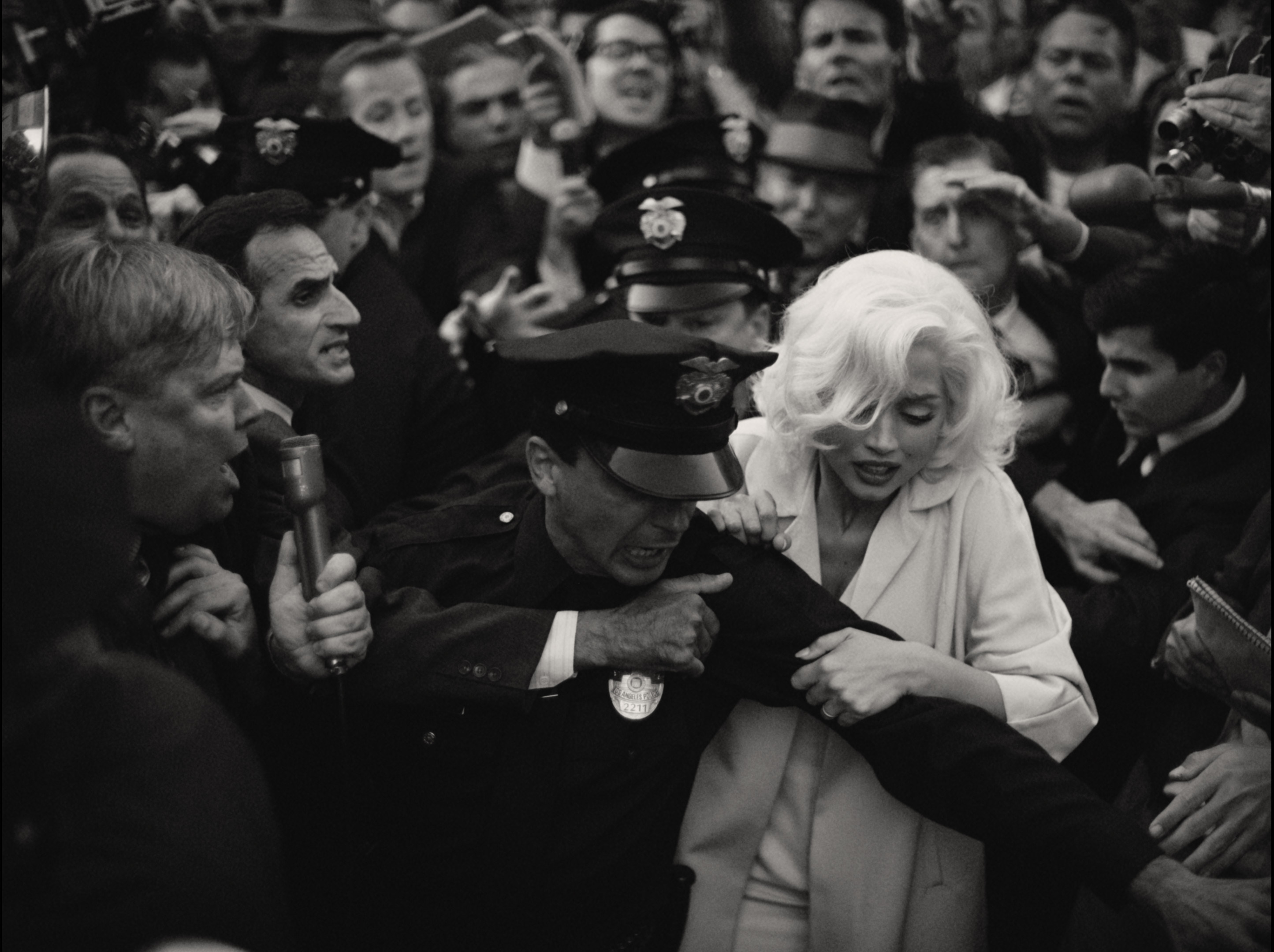 Ana de Armas as Marilyn Monroe being ushered through a crowd by a police escort