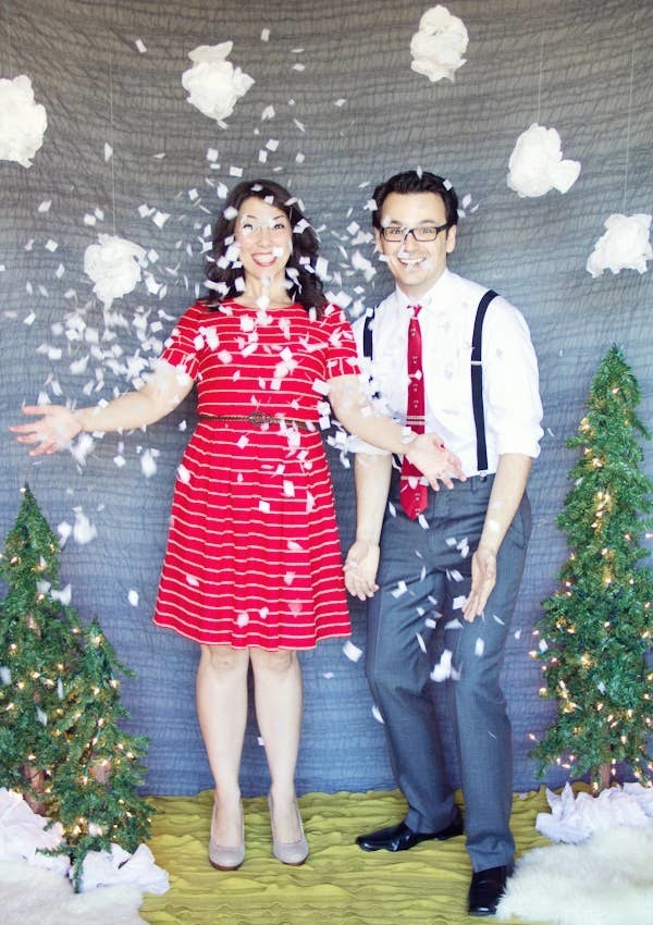 A man and a woman standing amid falling &quot;snow&quot; and small Xmas trees