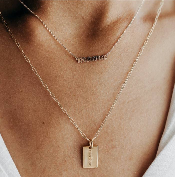 Two gold necklaces on a women&#x27;s neck. One says &quot;mama&quot; and the other says &quot;madison&quot;
