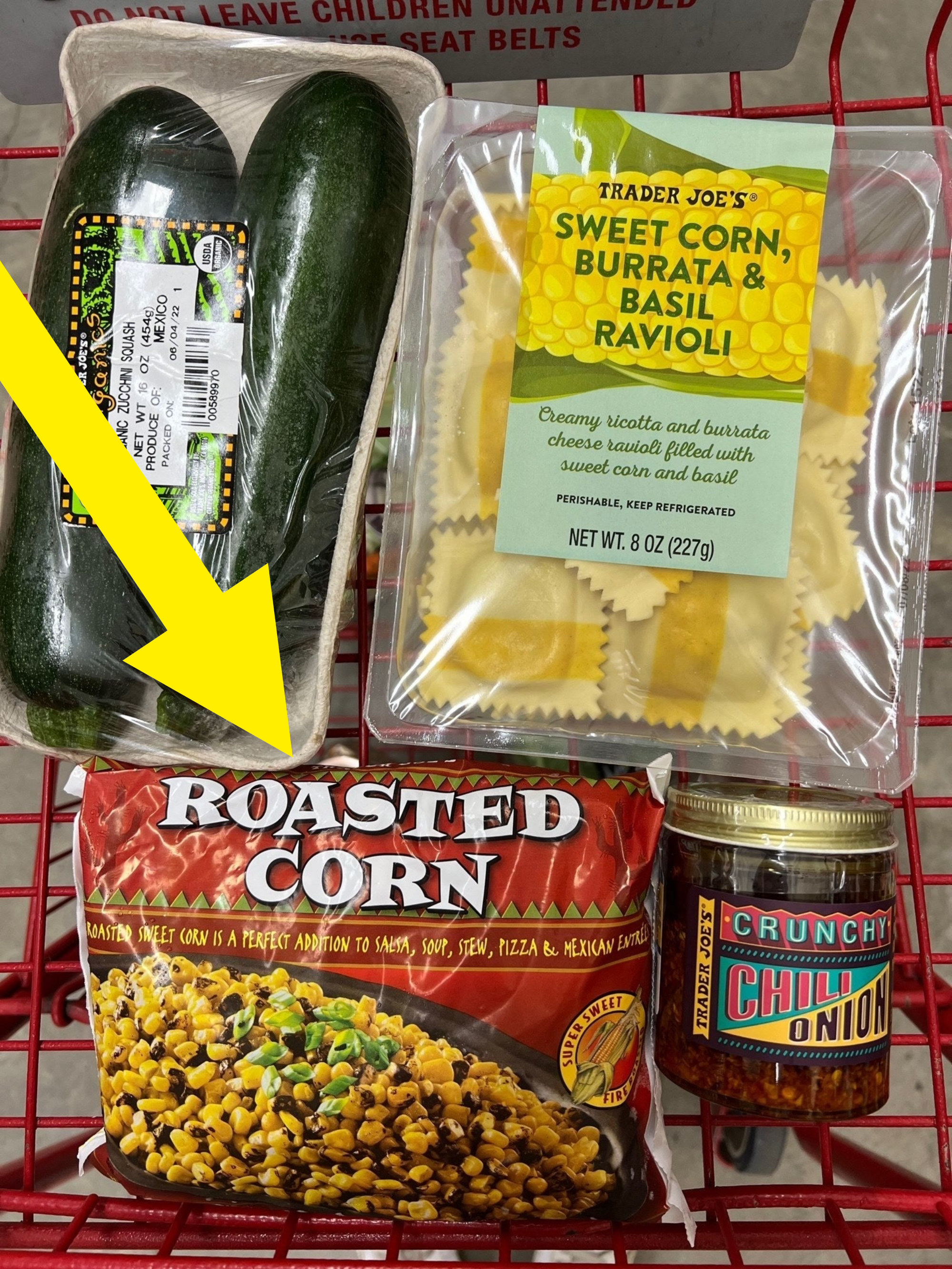 Ravioli, zucchini, frozen corn, and chili oil in a grocery cart.