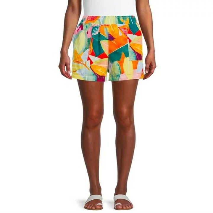 Model wearing colorful print shorts and white sandals