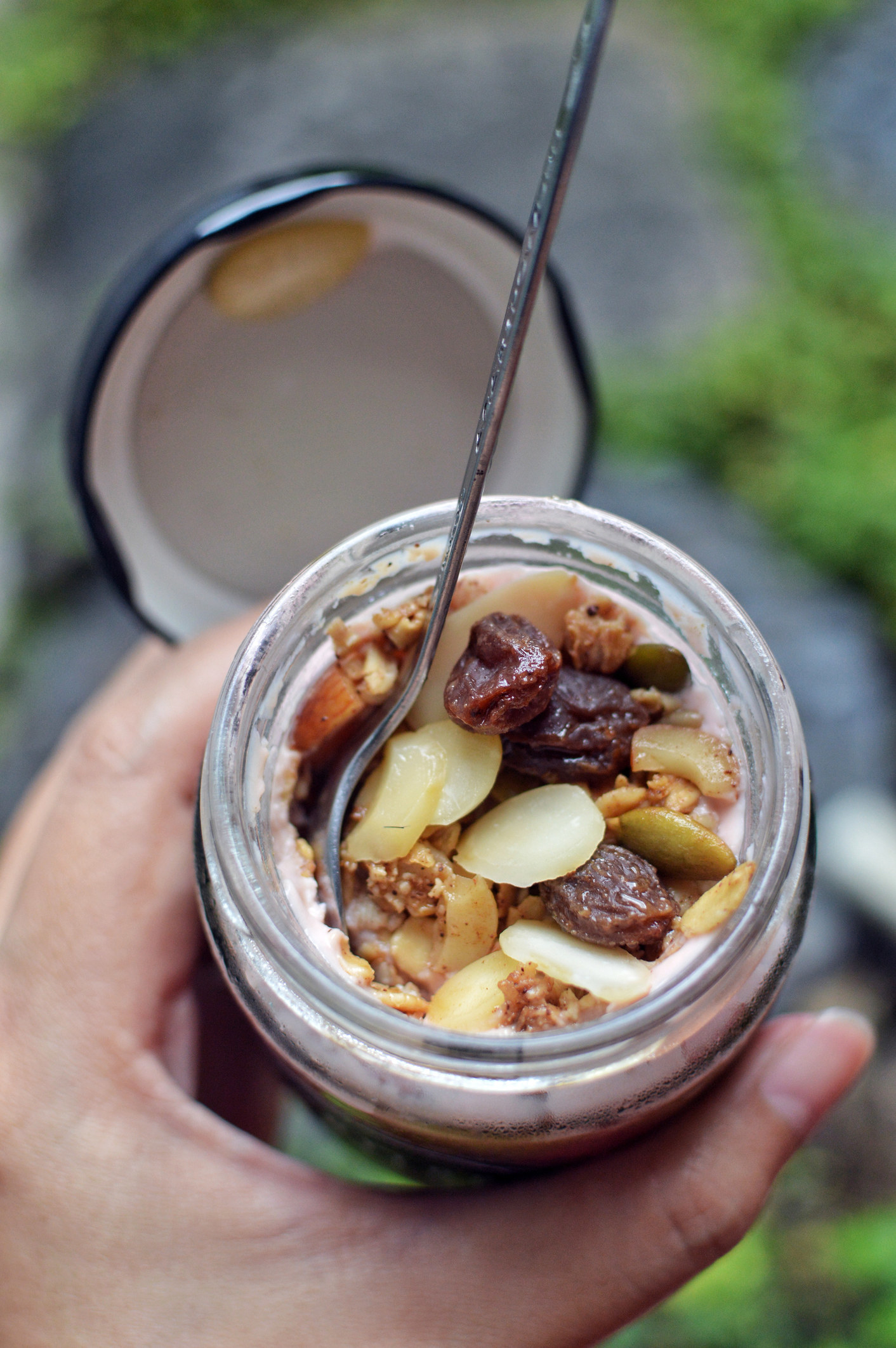 A jar of overnight oats with nuts and raisins.