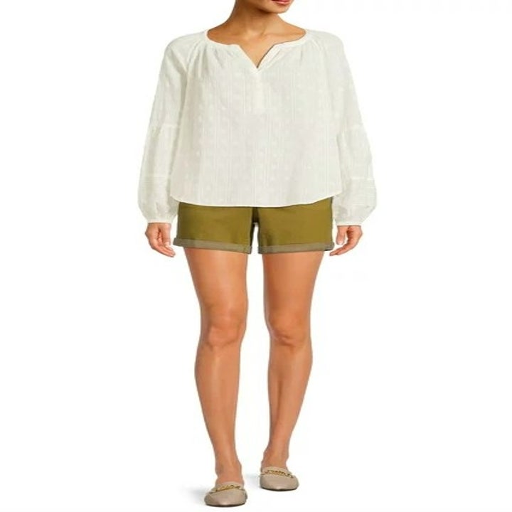 Model wearing green shorts, white top and neutral mules
