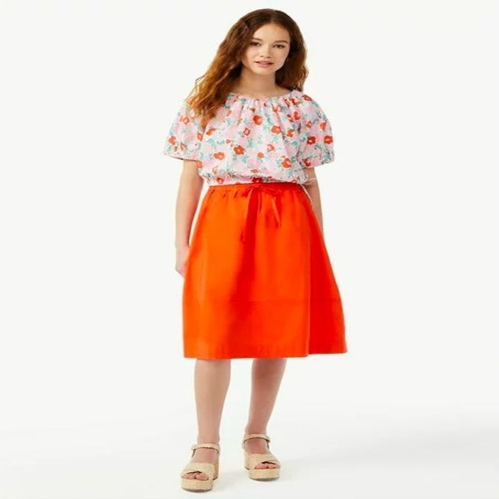 Model wearing orange skirt and floral top