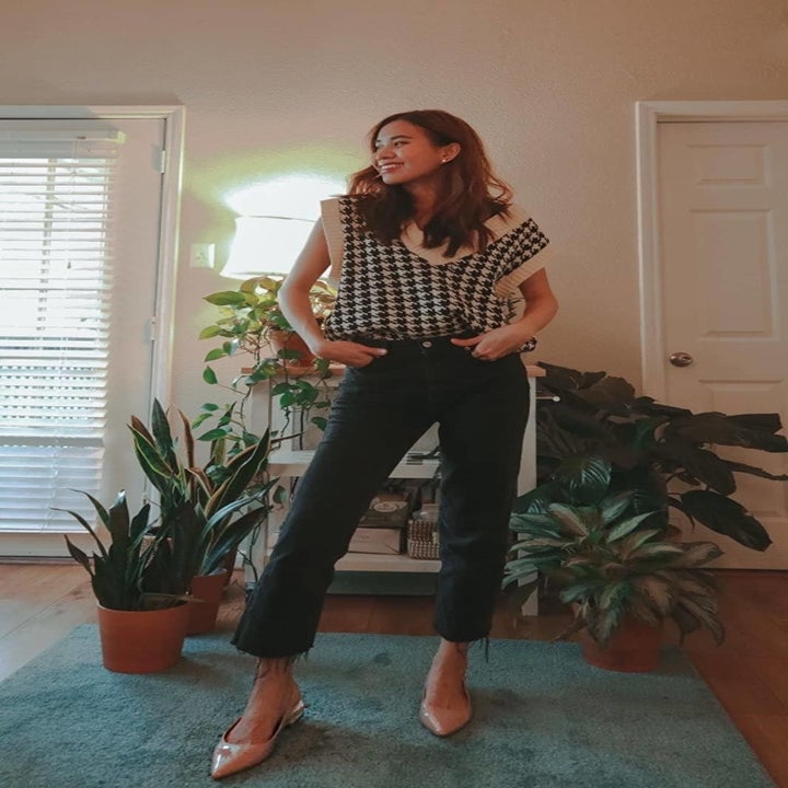 reviewer photo of them posing in a checkered sweater vest, black jeans, and nude heels