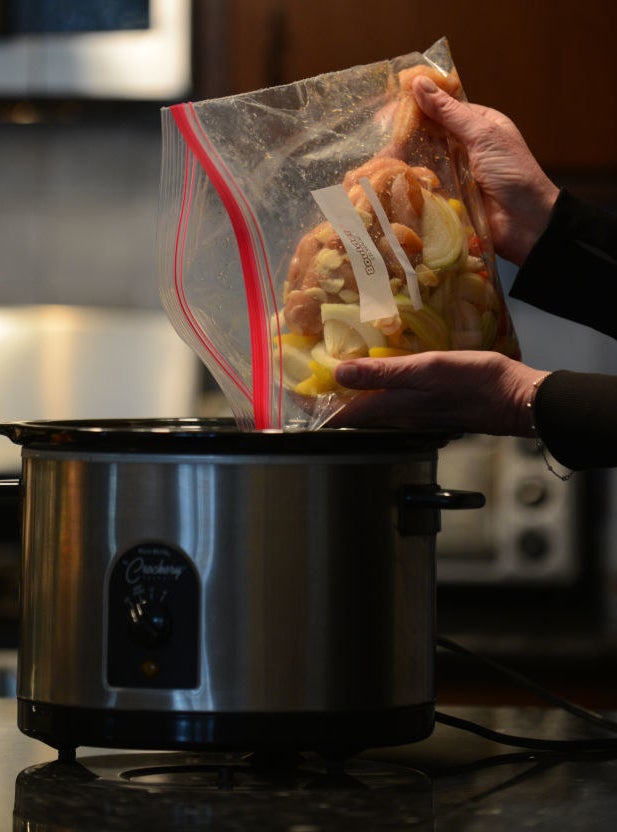 Pouring food into a slow cooker.