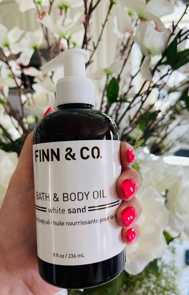 Reviewer holding Finn and Co bath and body oil