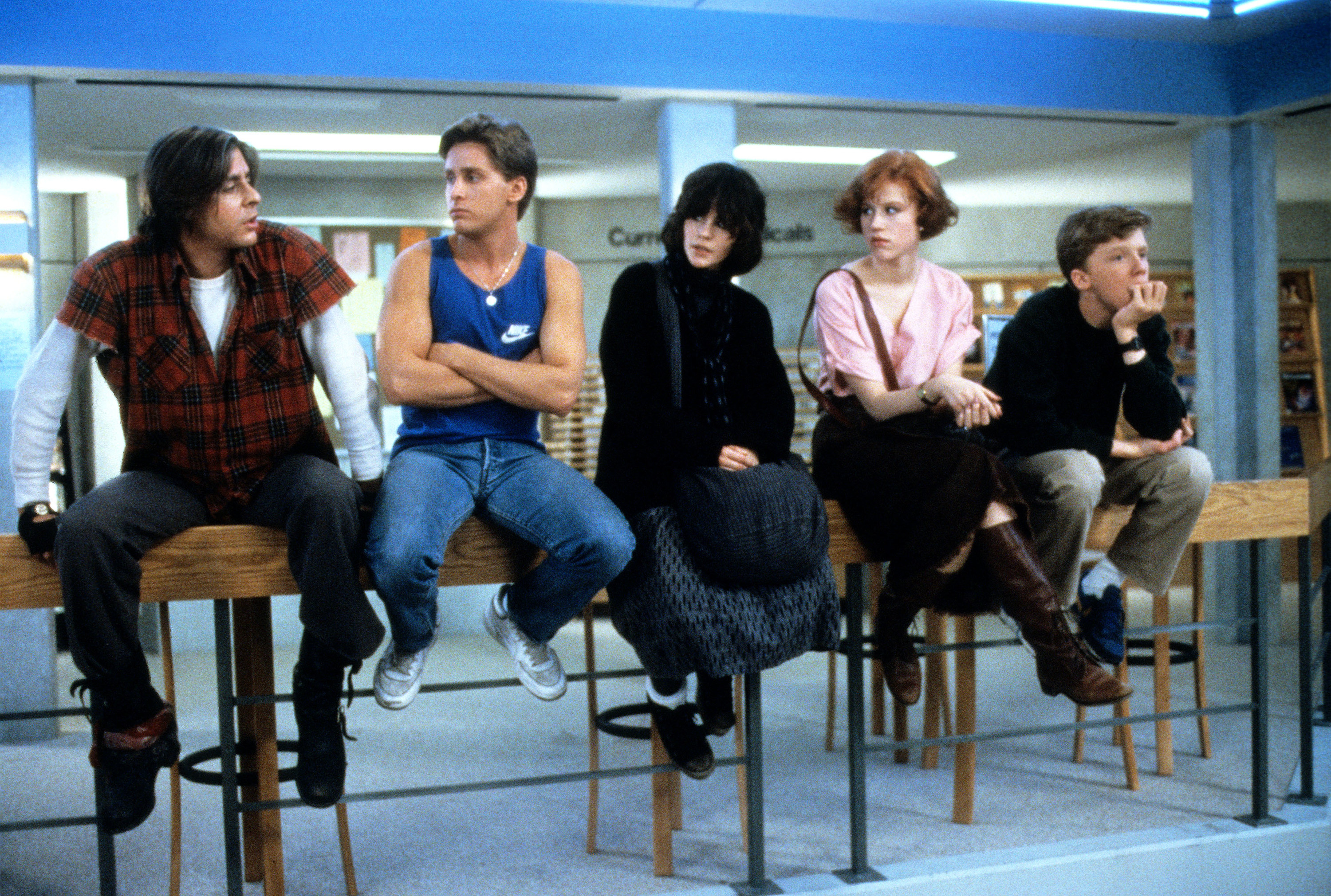 Judd Nelson, Emilio Estevez, Ally Sheedy, Molly Ringwald, and Anthony Michael Hall sitting on a bannister.