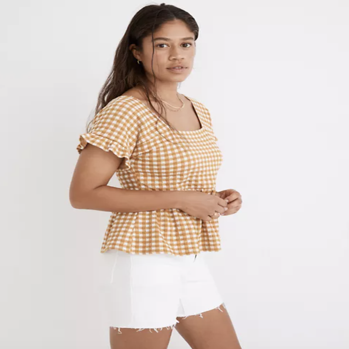 model wearing short-sleeve yellow and white-printed ruffle-hem top