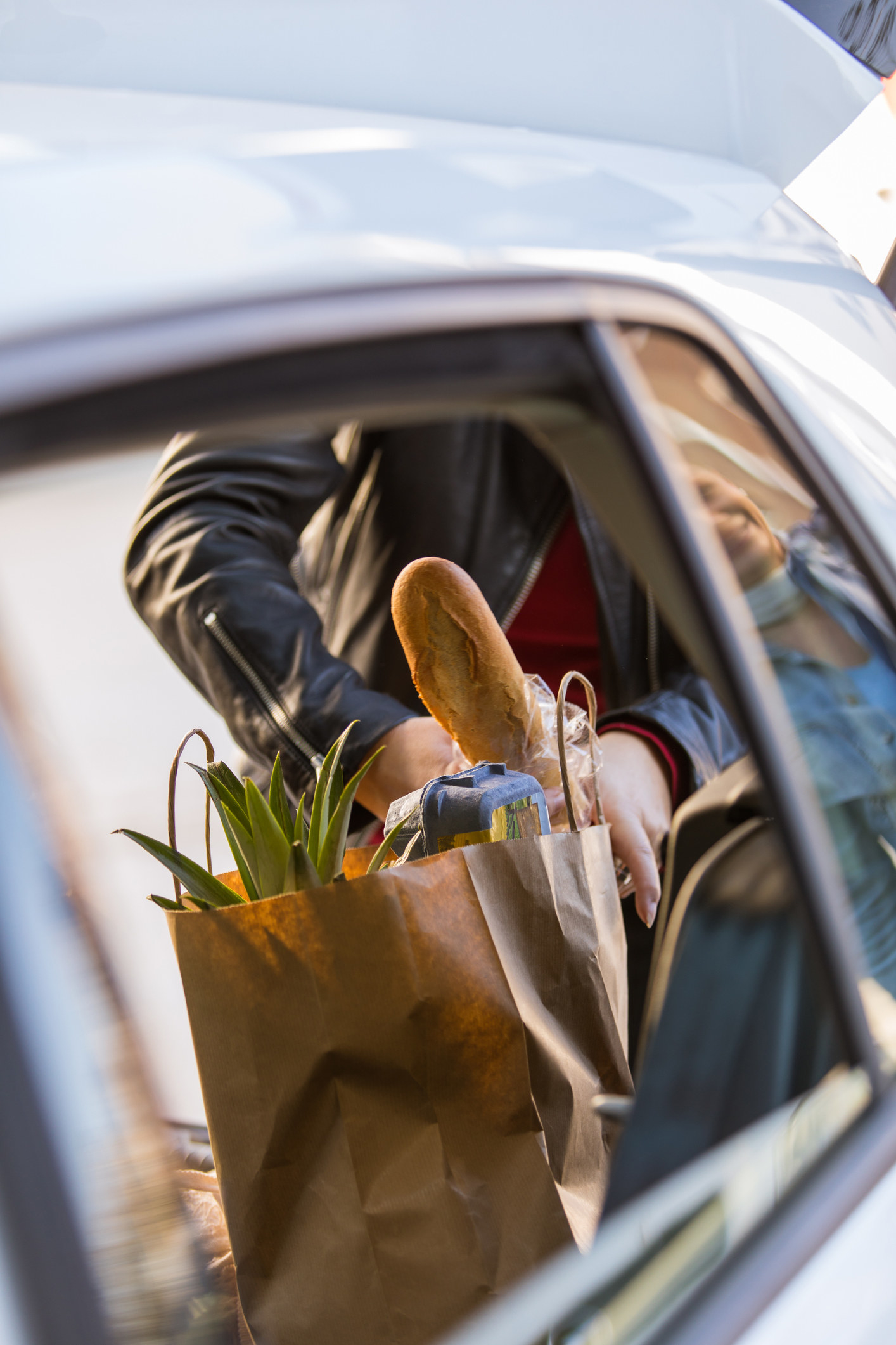 A person putting a grocery bag in the car.