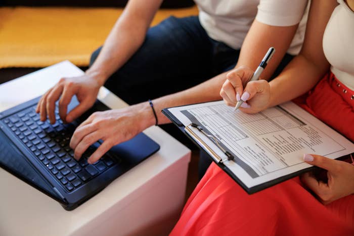 Young couple using a laptop and analyzing their finances with documents