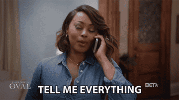 A gif of a woman on the phone smiling and saying &#x27;tell me everything&#x27;