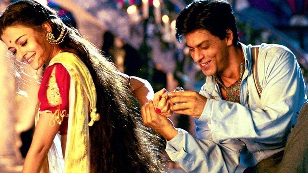 Aishwarya and Shah Rukh smile while he makes her try on a bangle