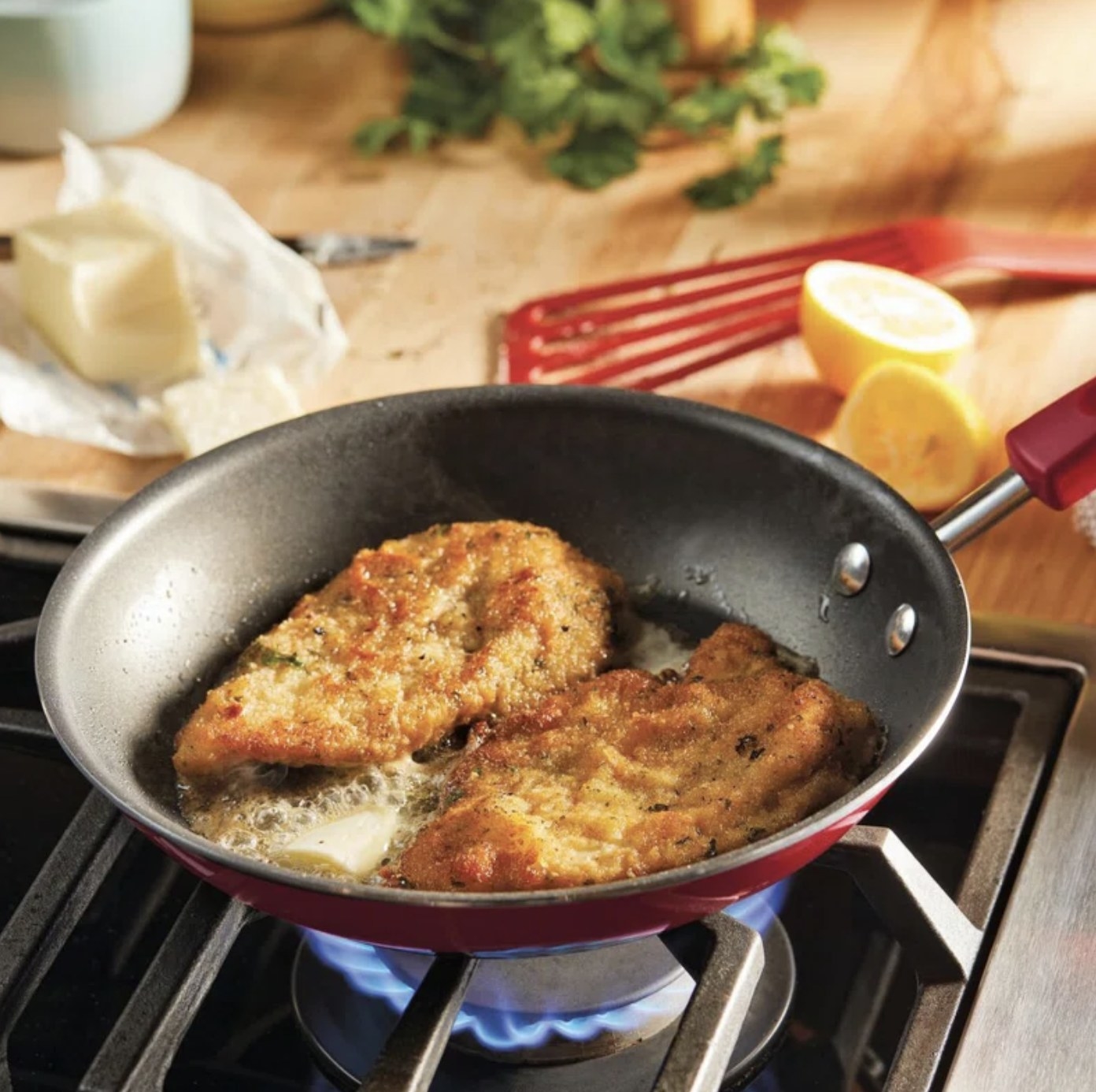 The red fry pan sizzling up breaded meat cutlets in butter