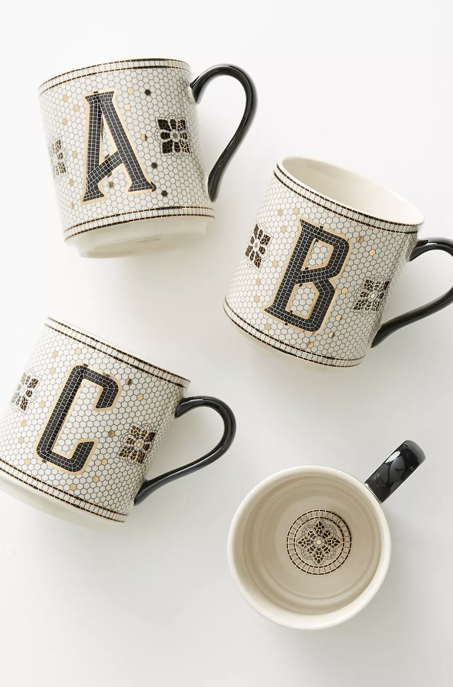 The monogrammed mugs with gold and black detailing on the white ceramic tile design in letters A, B and C