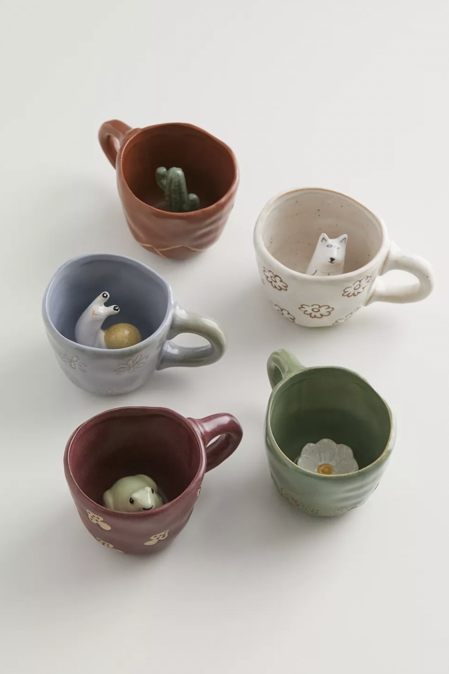 The various mugs with different ceramic animals and plants hiding at the bottom