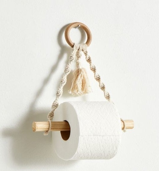 a macrame toilet paper holder hanging on a white wall
