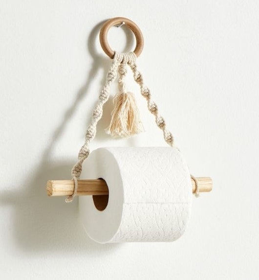 a macrame toilet paper holder hanging on a white wall