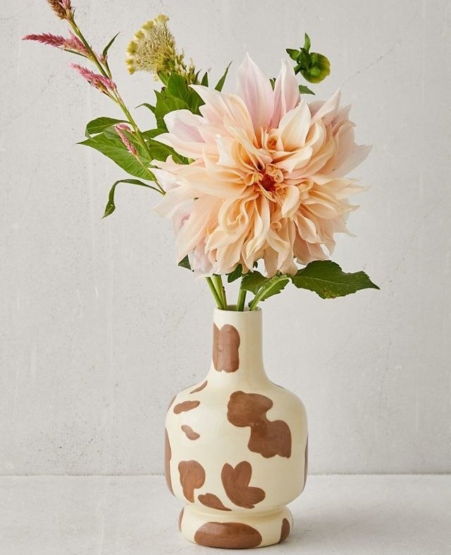 cow-print vase with a bouquet of flowers in it