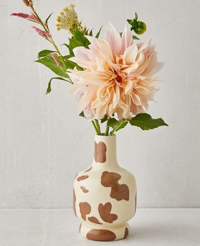 cow-print vase with a bouquet of flowers in it