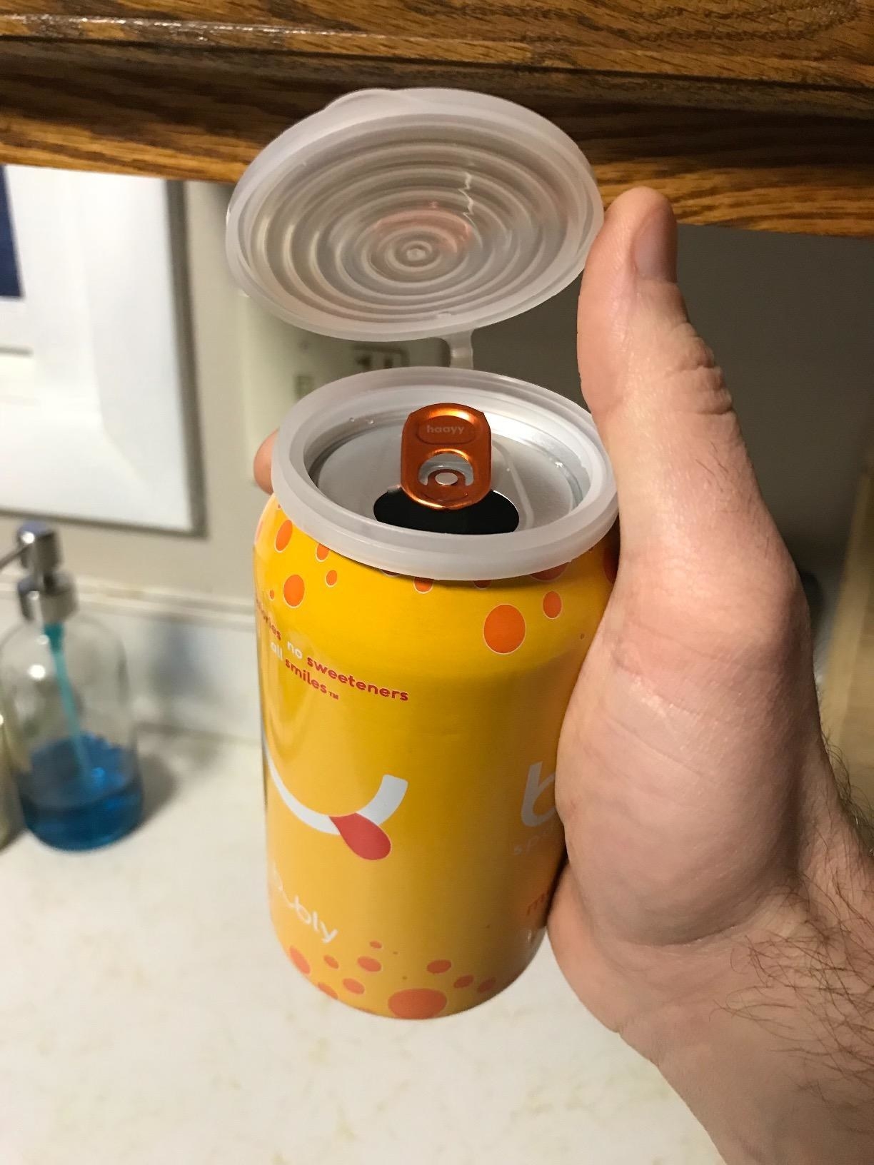 reviewer holding can of seltzer with clear cover snapped on