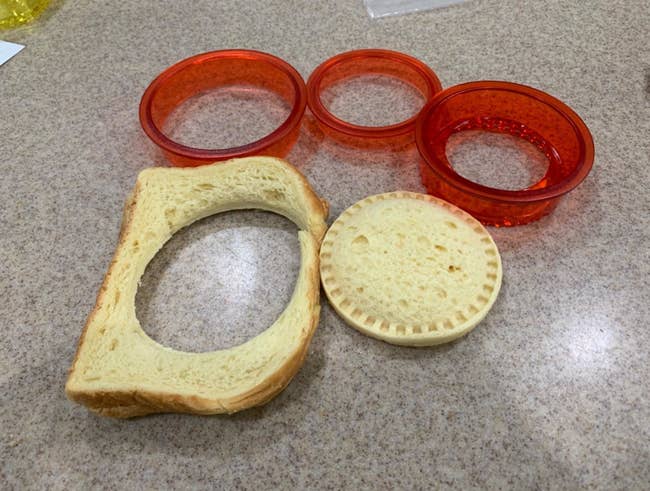 Reviewer's photo of the cutters next to a slice of bread with perfectly round uncrustable cut out