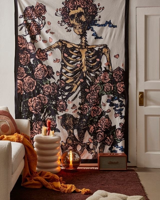 a rose covered skeleton wall tapestry on a wall in a living room
