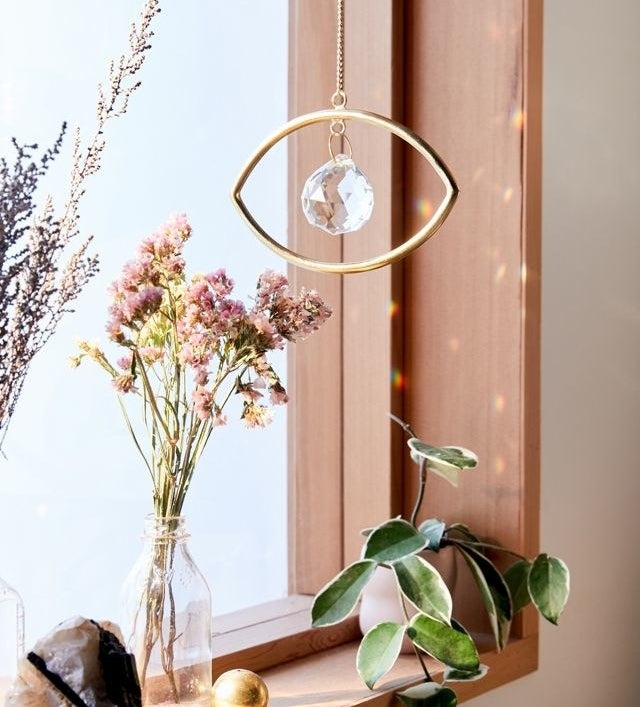 a hanging eye-shaped decor piece beside a bright window