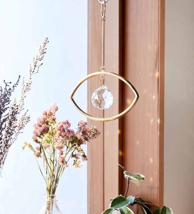 a hanging eye-shaped decor piece beside a bright window