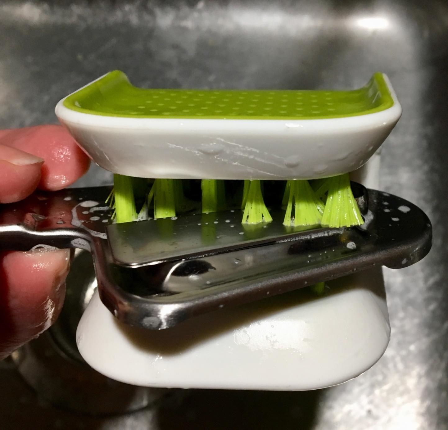 Reviewer using the green scrubber to clean sharp blade