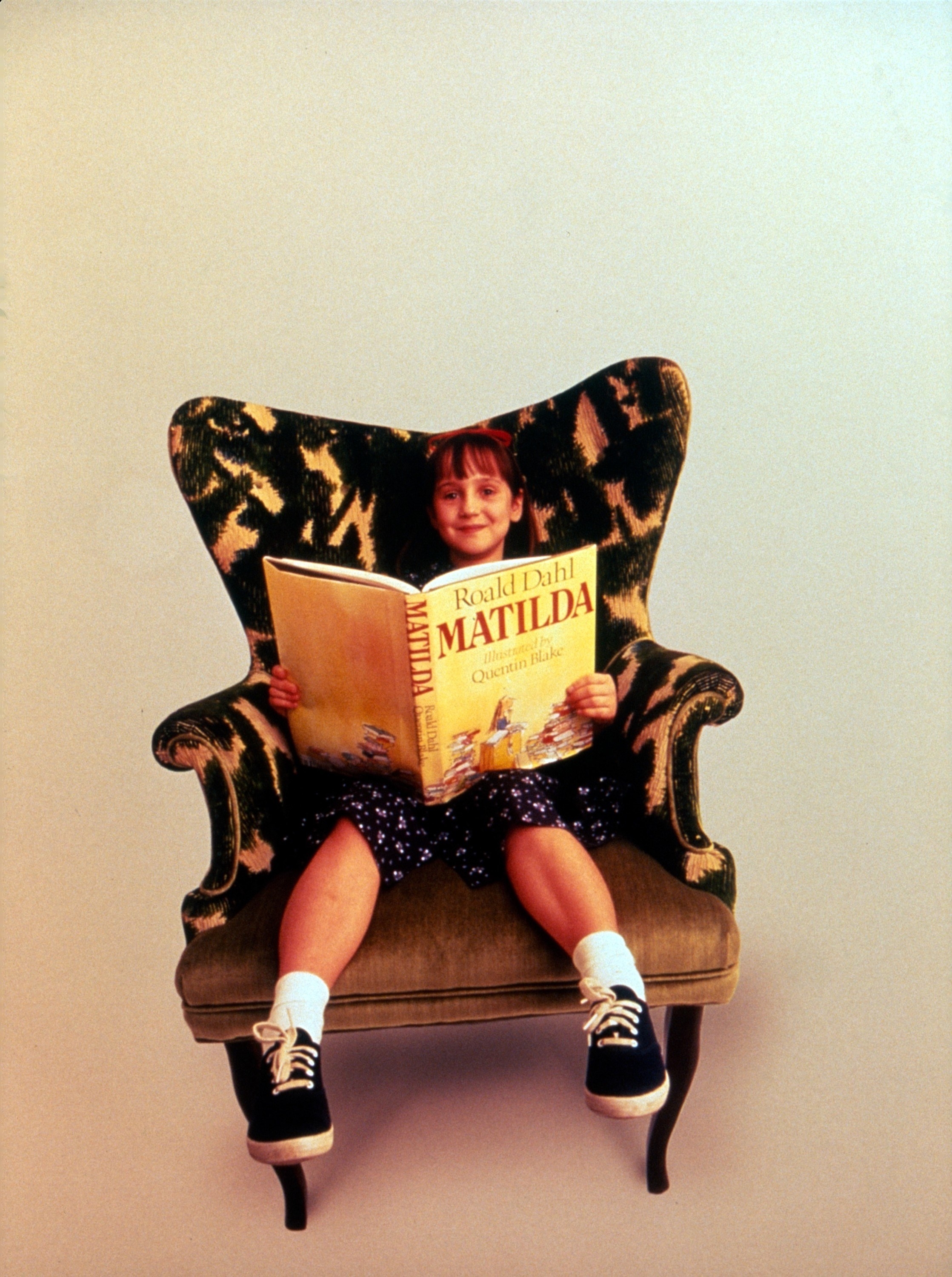 Mara sitting in a large chair while holding the book