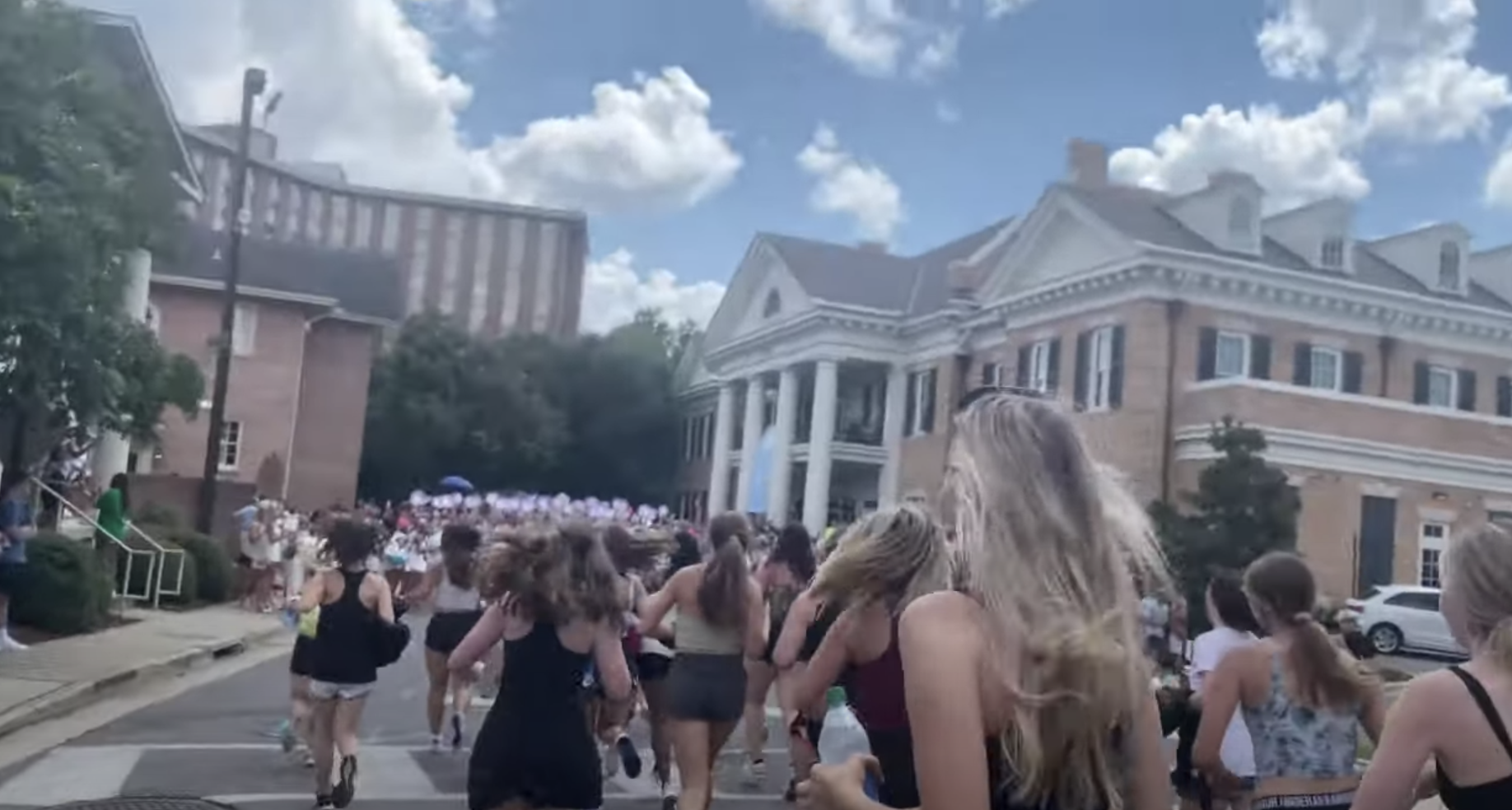 Young women running along the streets of a college campus