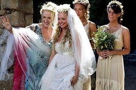 Sophie from Mamma Mia wearing her veil and wedding dress with her bridesmaids behind her and Donna next to her