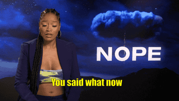 Keke Palmer in an interview setting with the nope film poster in the background saying you said what now