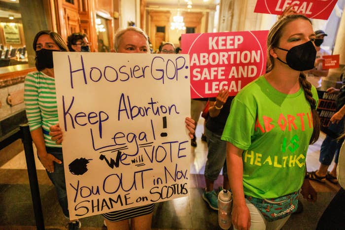 An abortion rights activist holds a sign reading, "We will vote you out in November"