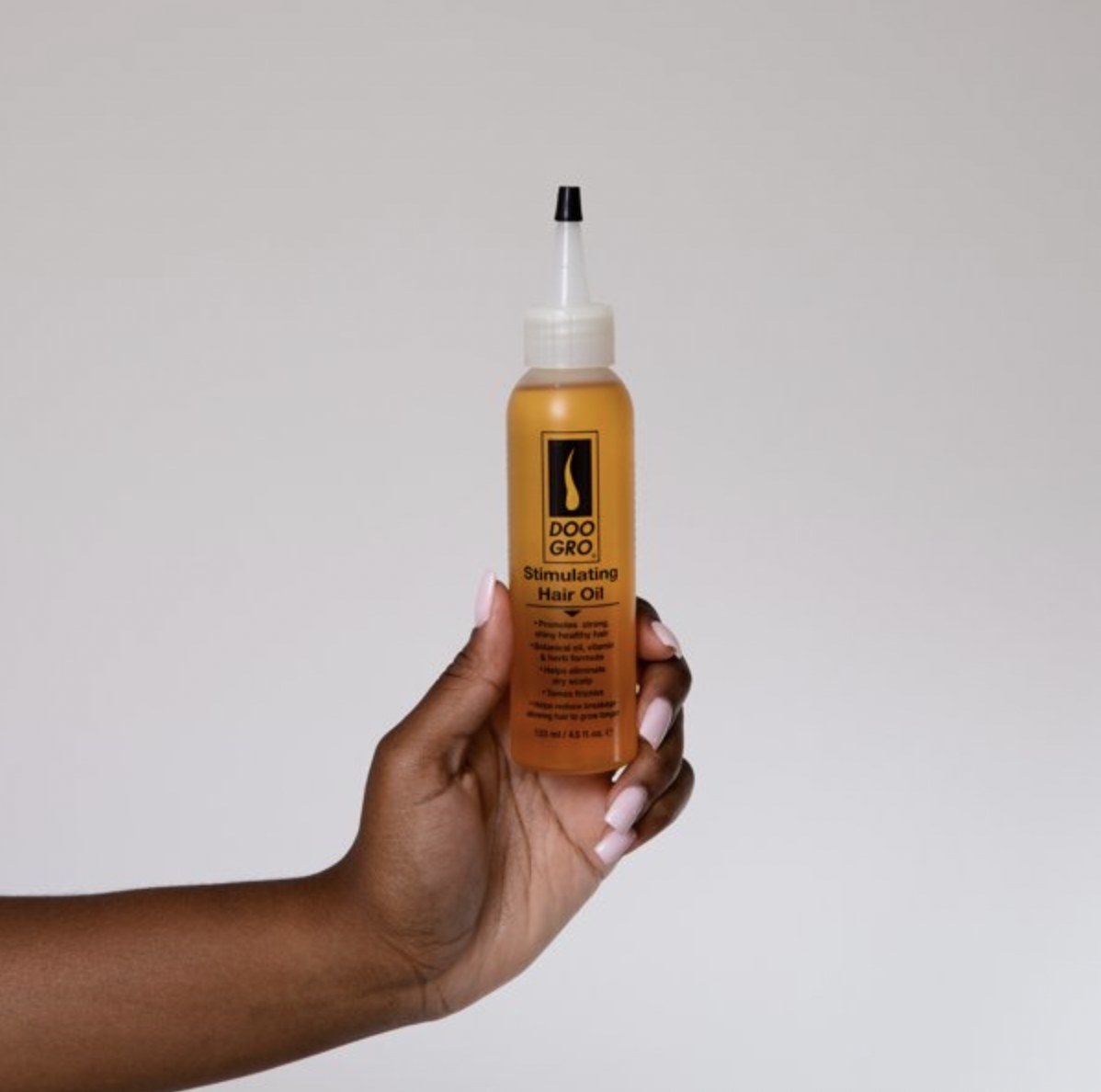 A person holding a bottle of hair oil
