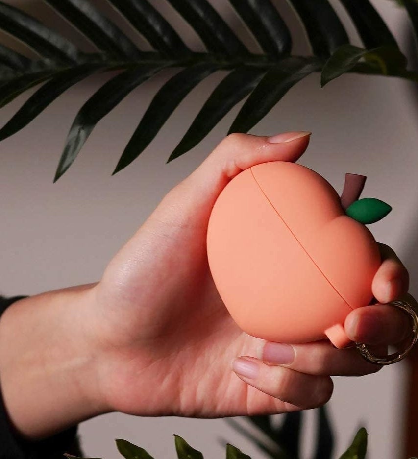 A person holding the peachy earpods case
