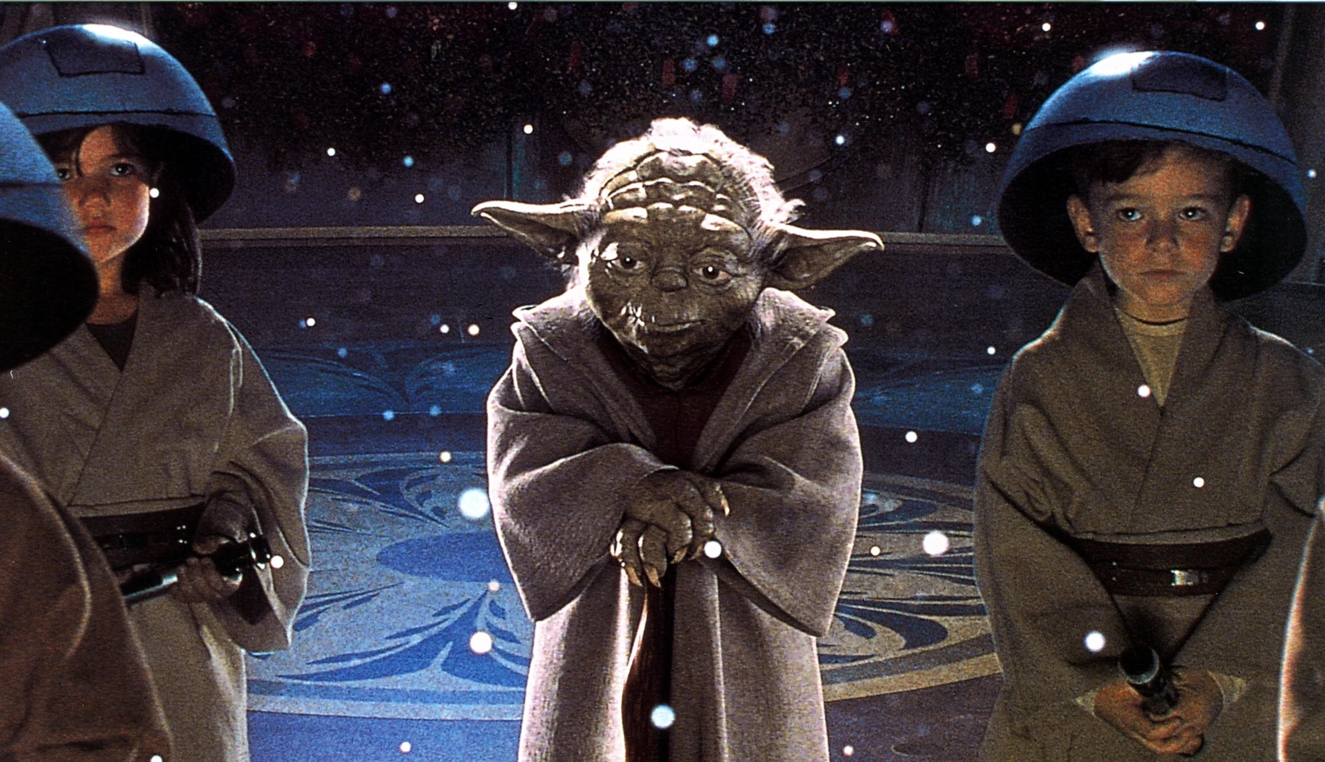 Yoda looks at someone while surrounded by two boys