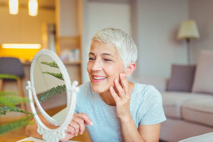 A woman smiles as she looks at herself in the mirror