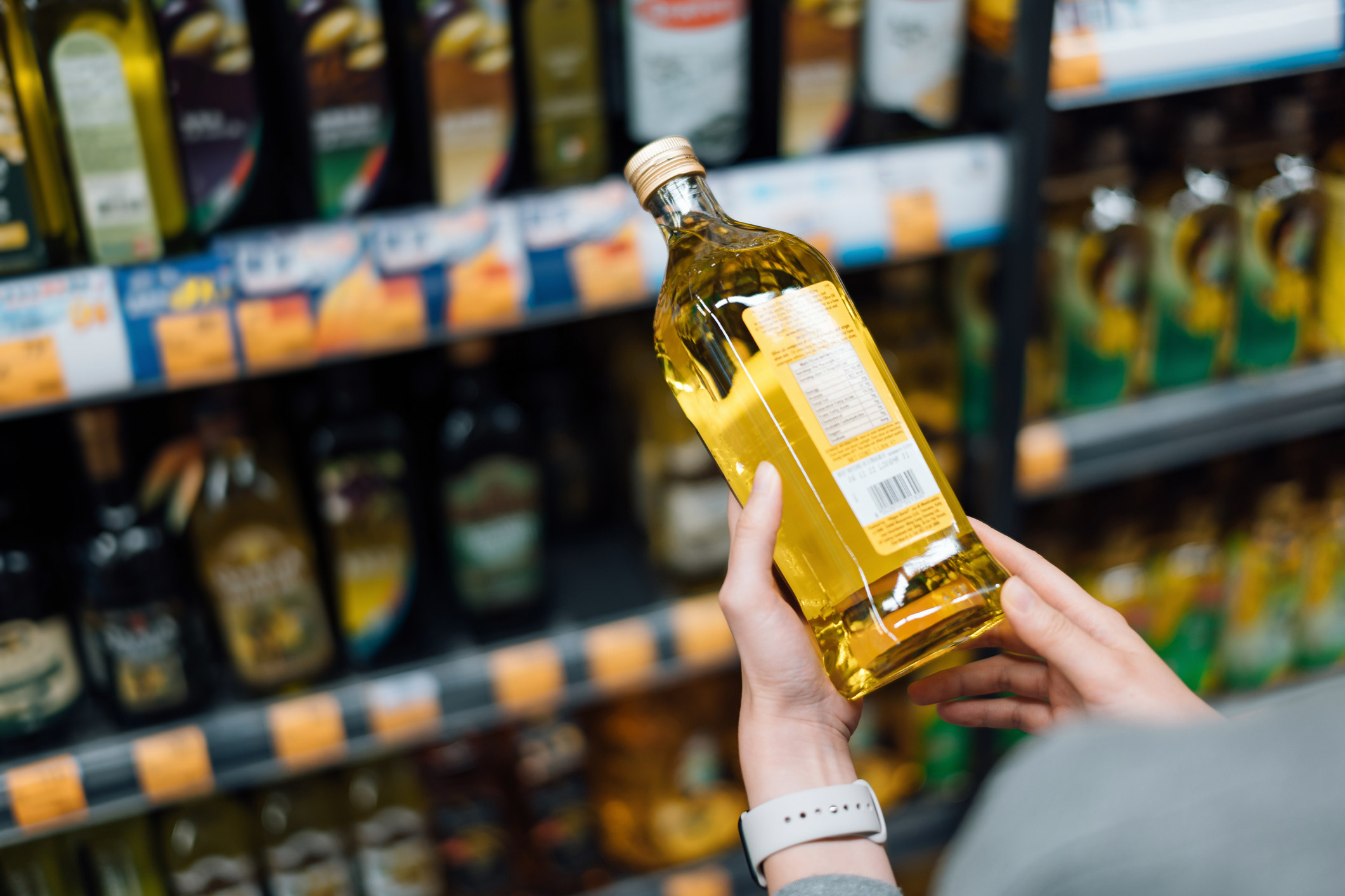 A person holds olive oil in the supermarket